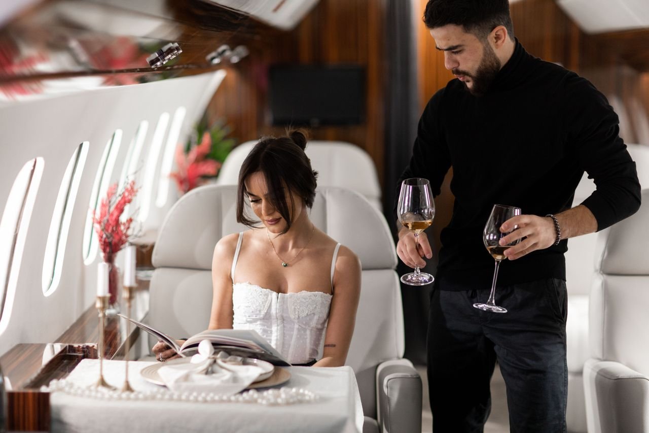 Services Elegant couple enjoying wine in a luxurious private jet interior.
